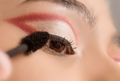Auftragen von rotem Lidschatten rund um das Auge mit einem Make-up-Pinsel