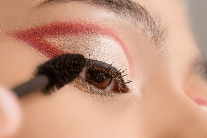 Auftragen von rotem Lidschatten rund um das Auge mit einem Make-up-Pinsel